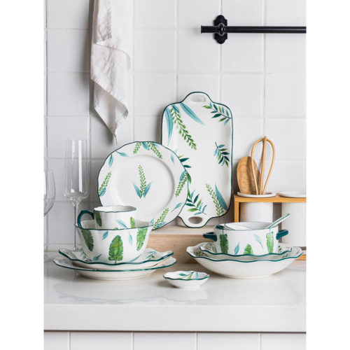 Белая керамическая посуда с рисунками зеленых листьев